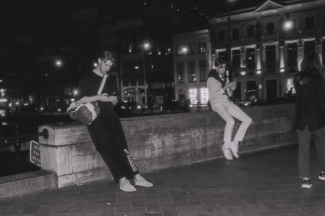 a black-and-white photograph of people beside a canal at night