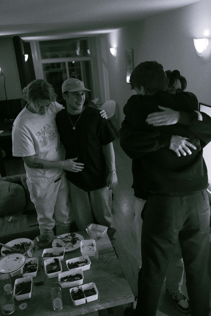 a black-and-white photograph of friends gathered around a table