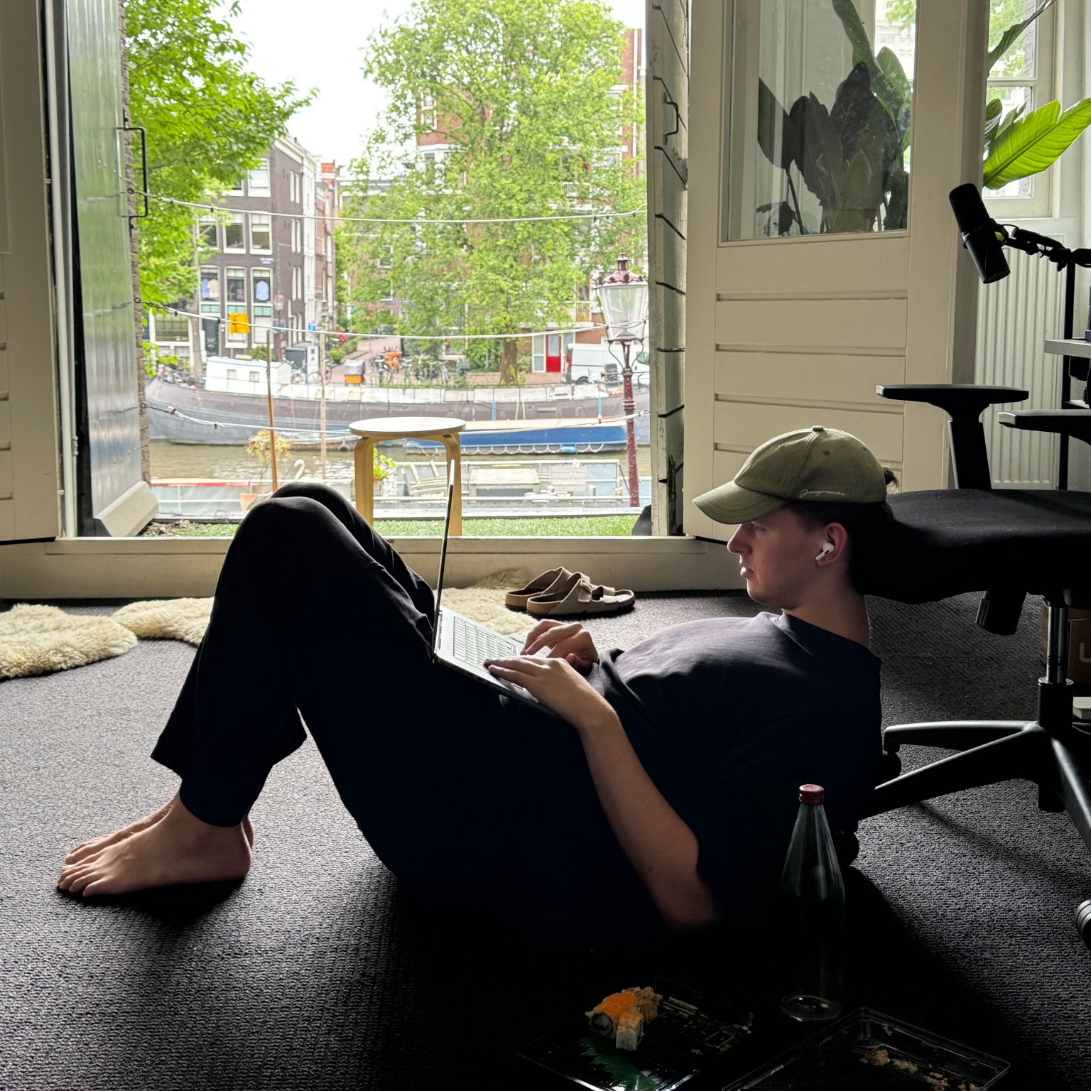 working on a laptop on the office floor beside the open canal-facing windows